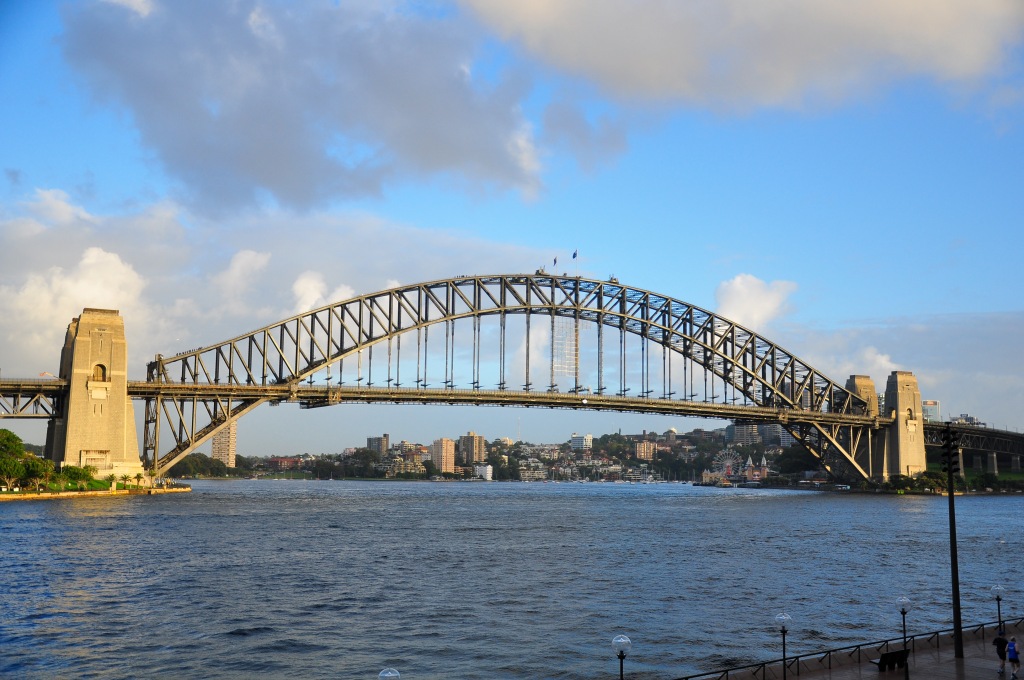 Sydney Harbour Bridge in the early morning, with the sun shining on the bridge.